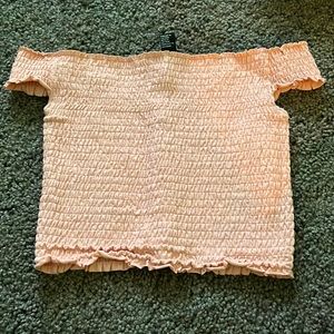 Off the shoulder light pink shirt.